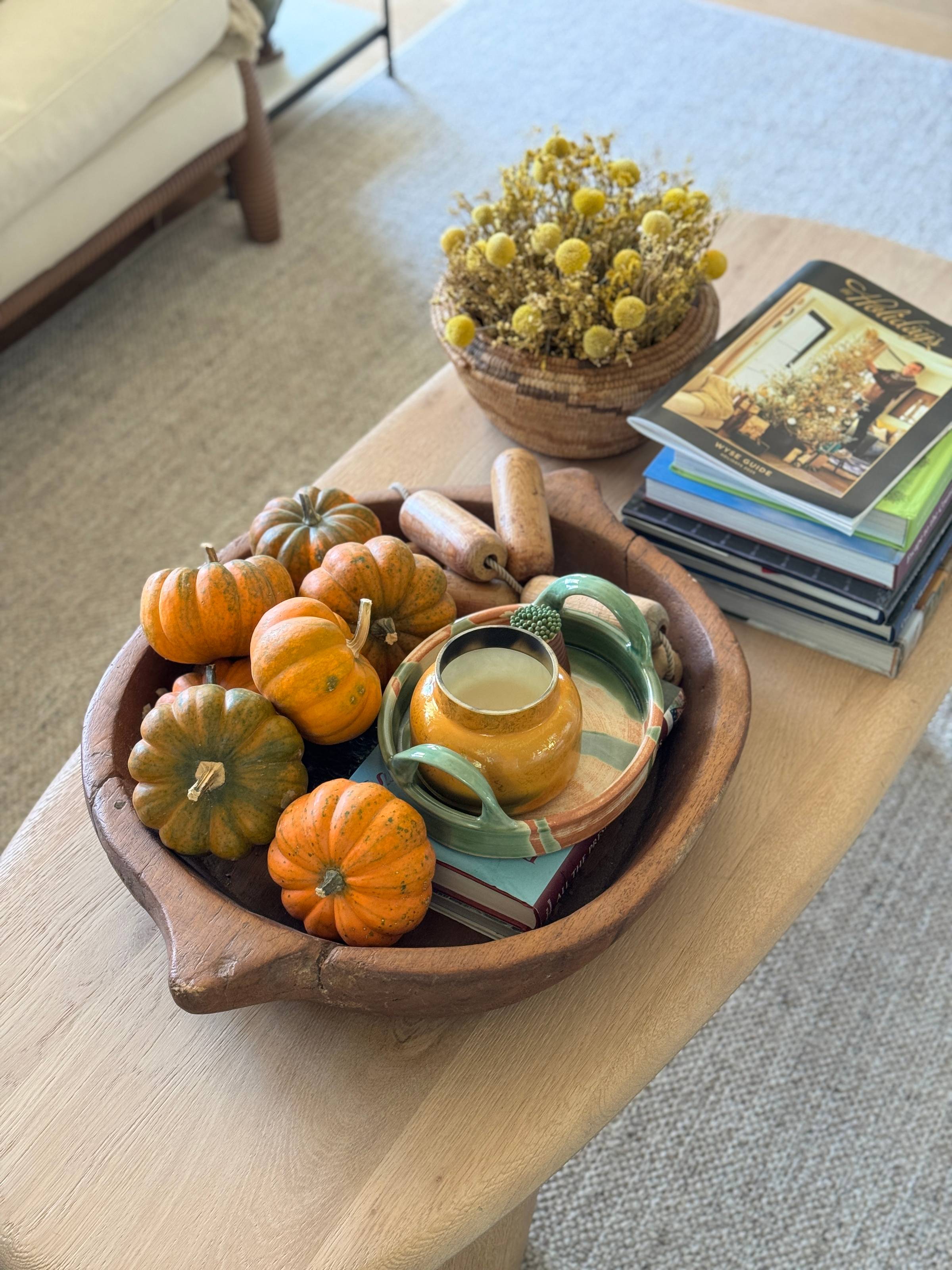 Brown bowl filled with pumpkins and a pumpkin candle.