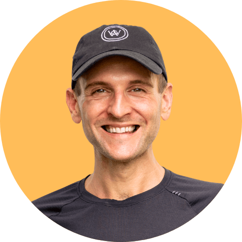 Kaleb Wyse wearing black hat and shirt standing in front of orange background.