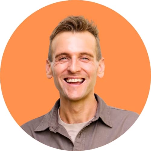 Kaleb Wyse standing in front of orange background smiling.