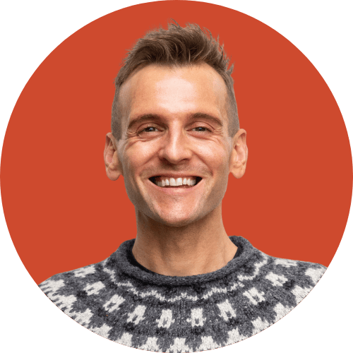 Kaleb Wyse wearing sweater standing in front of red background.