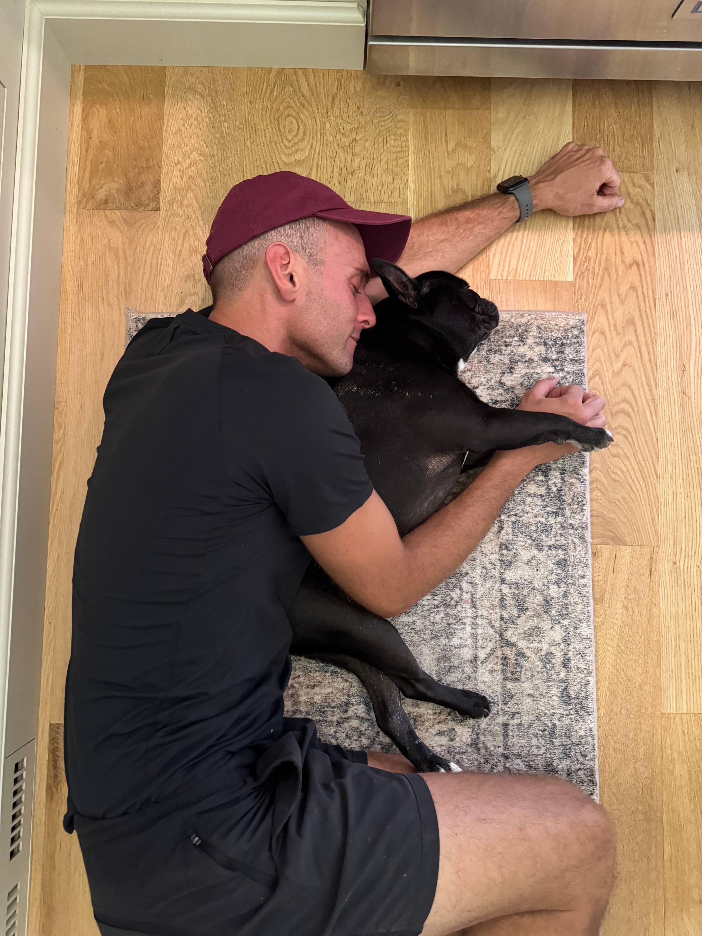 Kaleb Wyse with black French bulldog lying on the floor.