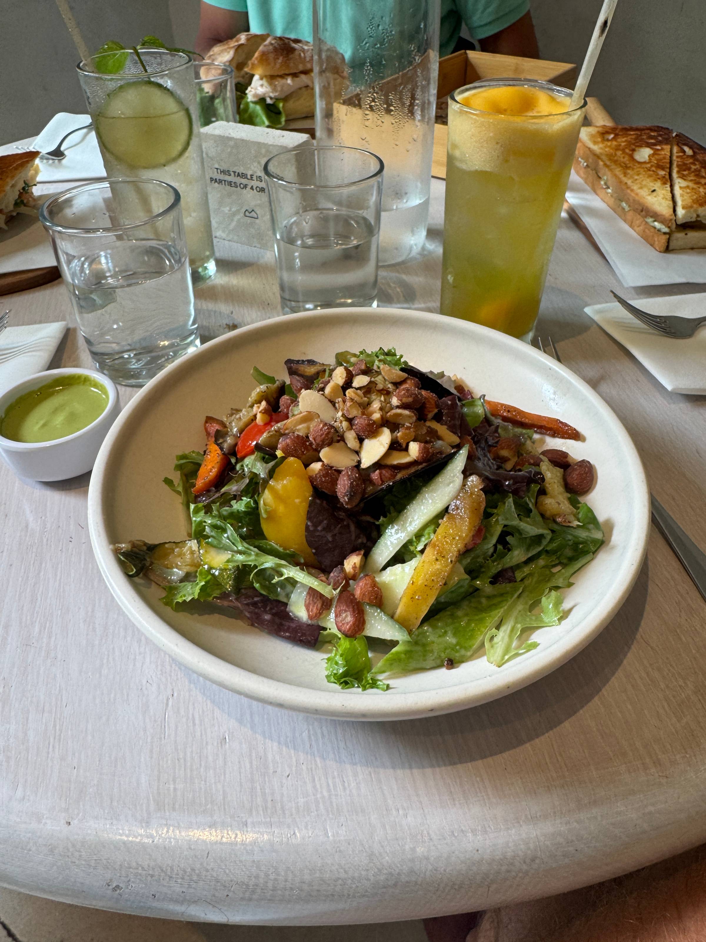 White plate with salad with almonds on top.
