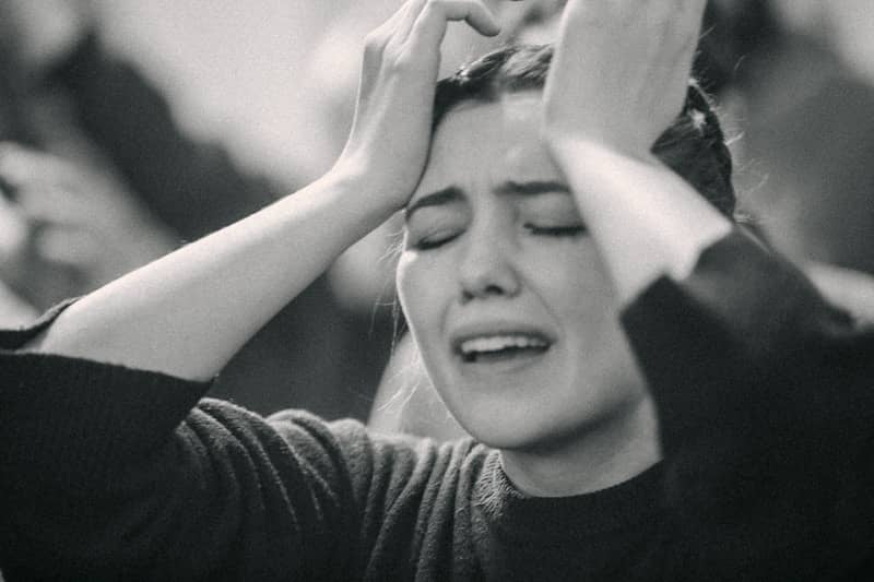 A black and white photo of a woman covering her eyes