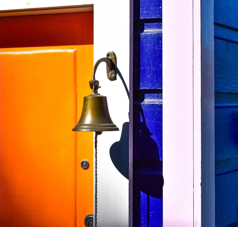 Brass bell hangs on a colorful door