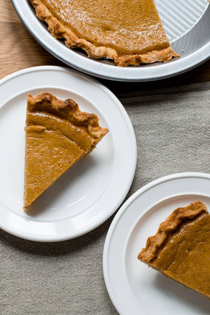 Slices of homemade pumpkin pie on white plates.