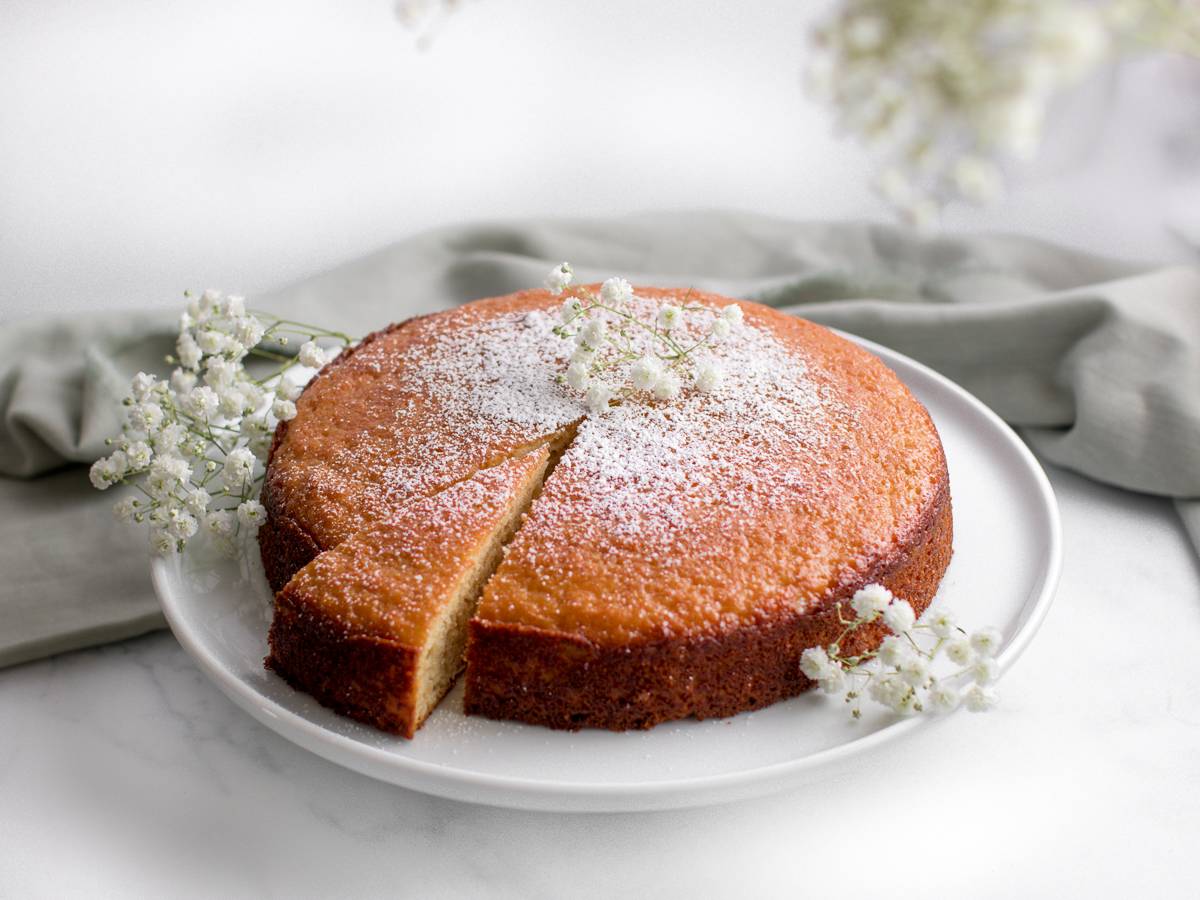 French yogurt cake with a slice removed, dusted with powdered sugar.