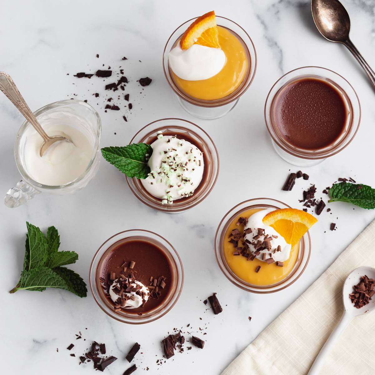 Chocolate Panna Cotta with various toppings like mint, cream, and orange curd.