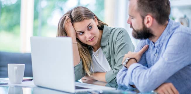 Woman sitting at a laptop discussion options intently with a man beside her