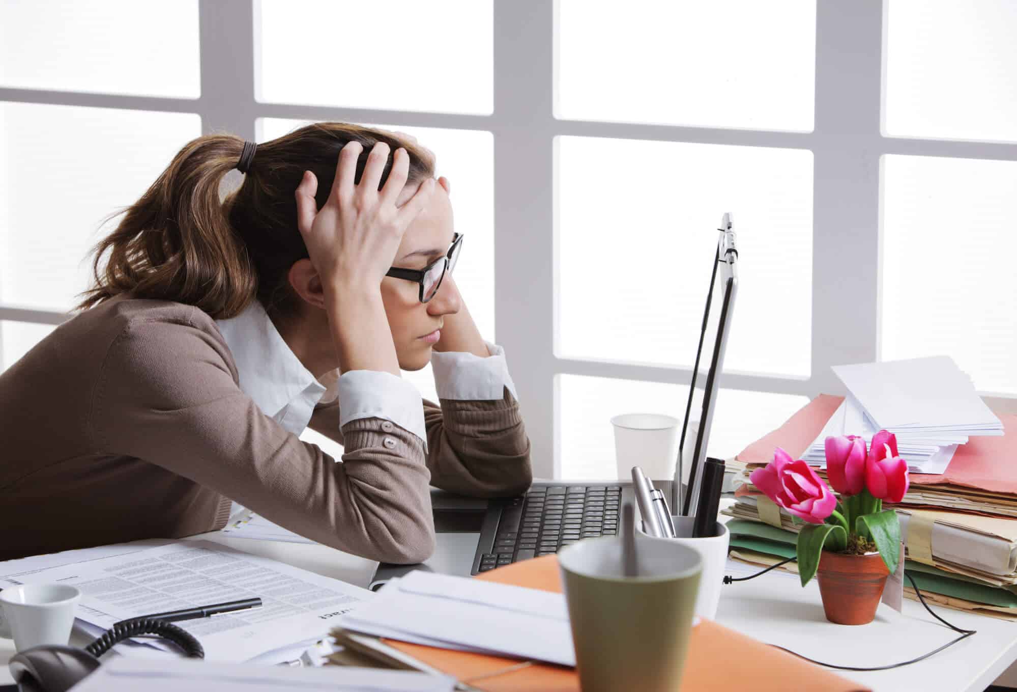 stressed teacher sitting at her desk surrounded by paper, staring at computer screen wondering what to do next.