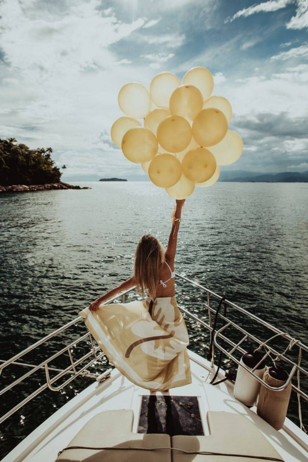 “From an article about adding micro moments of joy by Tess Rene Coaching — a woman holding yellow balloons on a boat, symbolising playfulness, freedom, and everyday joy.”