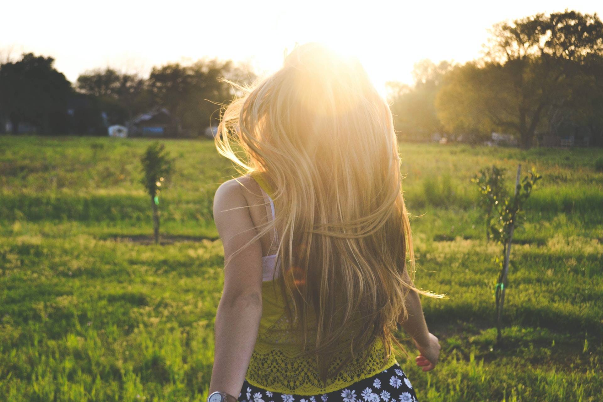 A photo of a blonde woman running into the sunset in nature