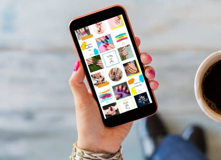 A hand wearing pink nail polish holds a phone showing a bright colored Instagram feed