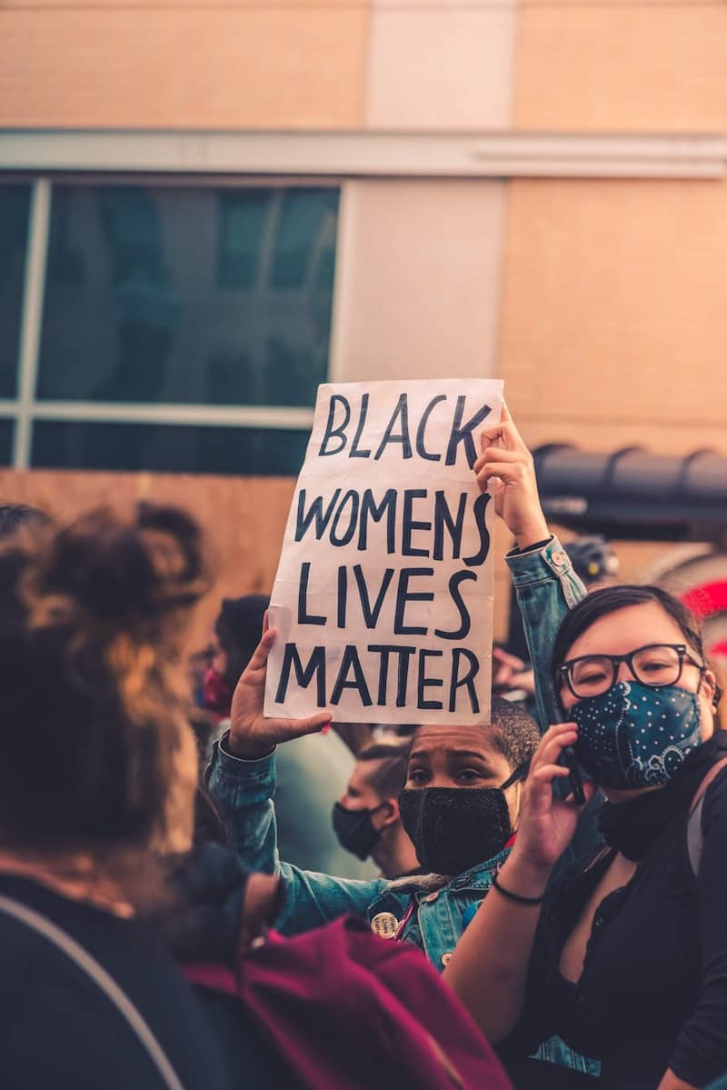 woman in blue denim jacket holding white and black happy birthday signage