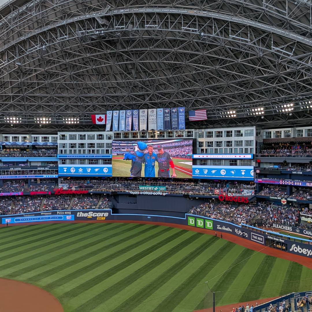 Canadian astronaut Jeremy Hansen on the big screen with mascot Ace and a Jays player