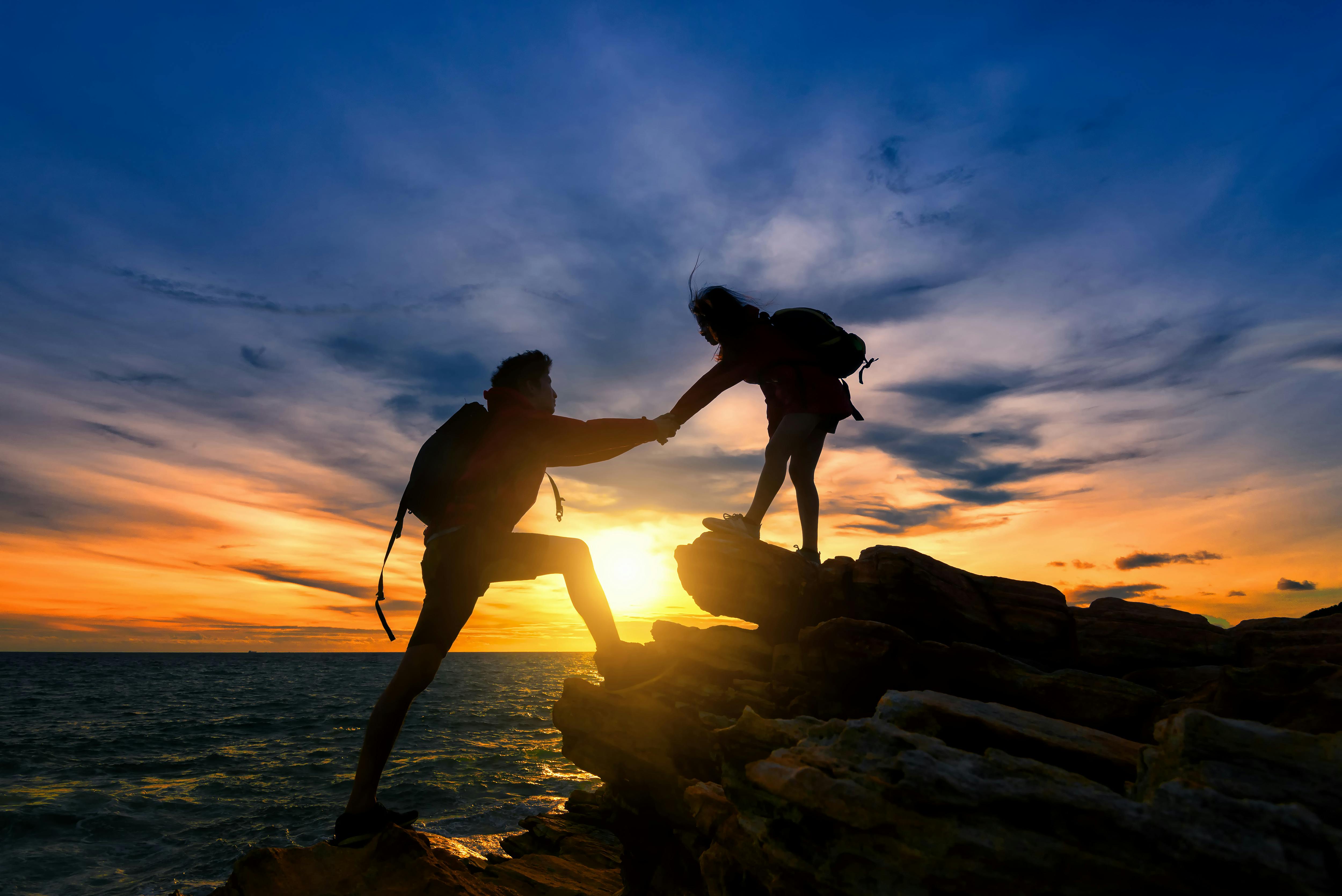 Young asian couple climbing up on the mountain,hiking and team work concept.