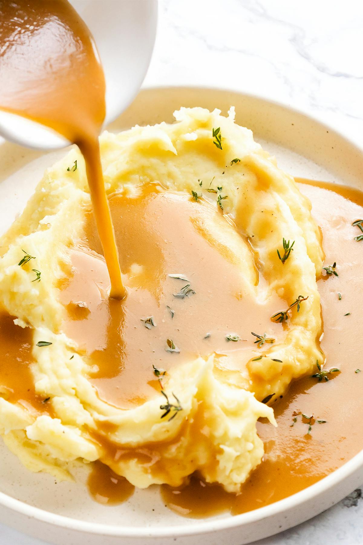 delicious creamy gravy being poured over mashed potatoes