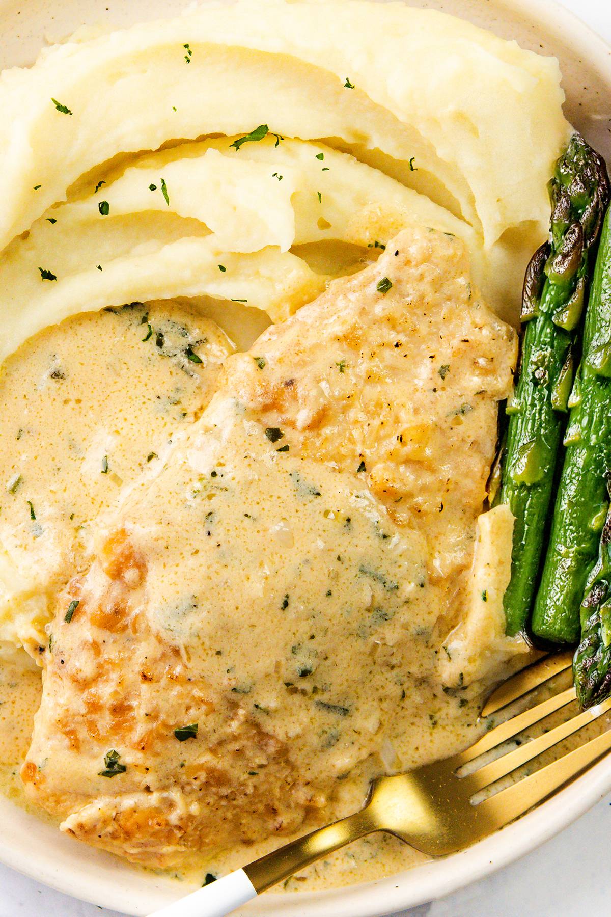 chicken with a creamy mustard sauce on top served with mashed potatoes and asparagus