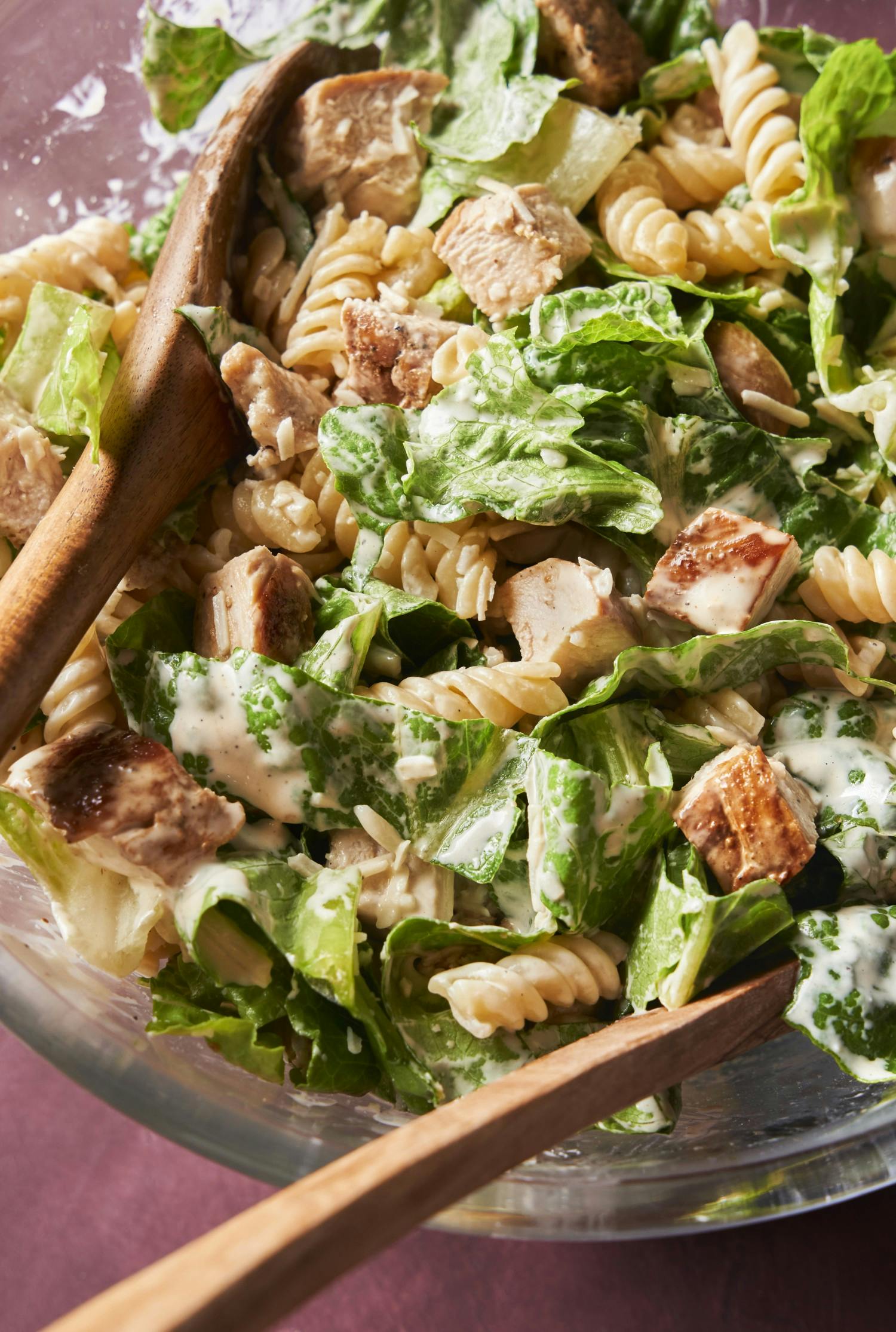 a pasta salad with chicken, romaine lettuce and casesar dressing.