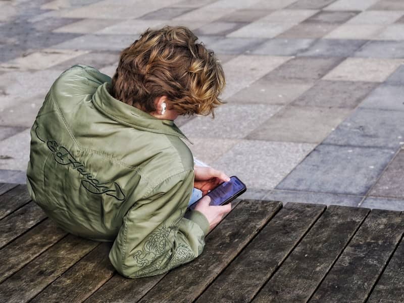 Young person with curly hair using a smartphone.