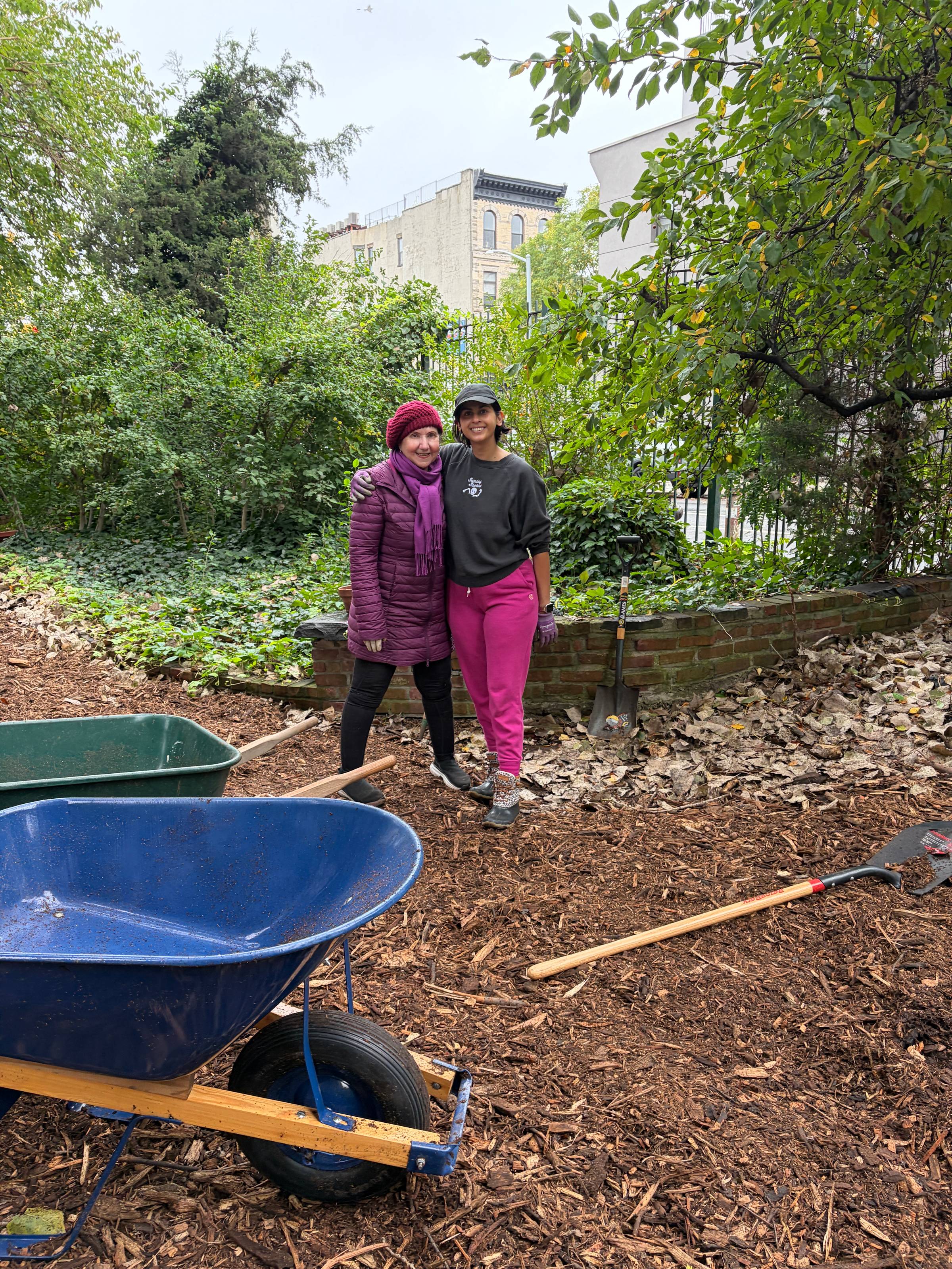 People in a neighborhood garden standing over mulch they have spread.
