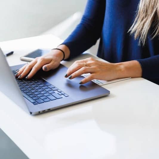 woman in blue long sleeve shirt using macbook pro