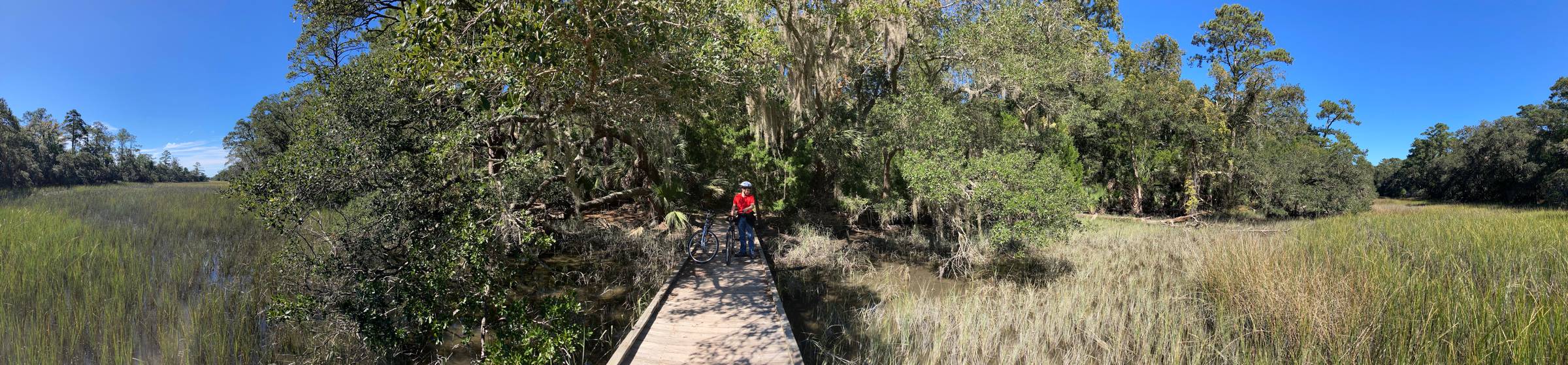 My brother standing with his bike on a boardwalk over a marsh