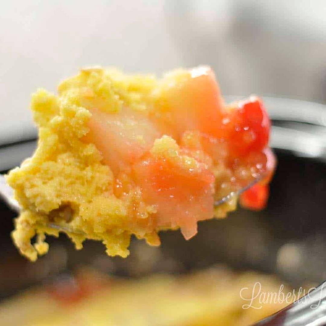 spoonful of tropical dump cake above a crock pot.