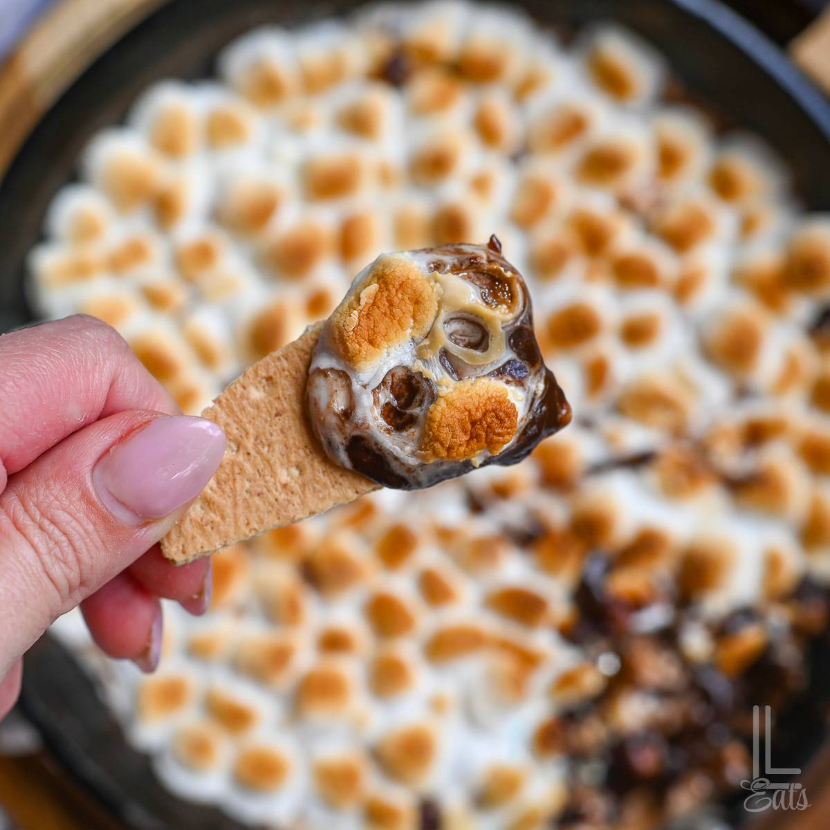 scooping smores dip with a graham cracker.