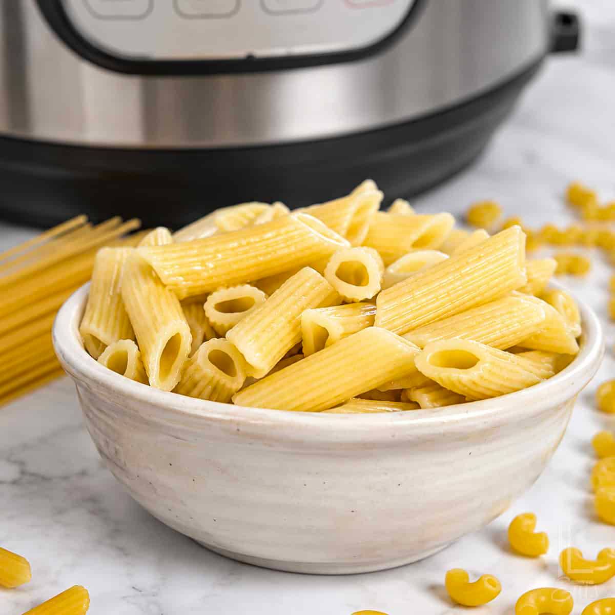 bowl of pasta in front of an instant pot.