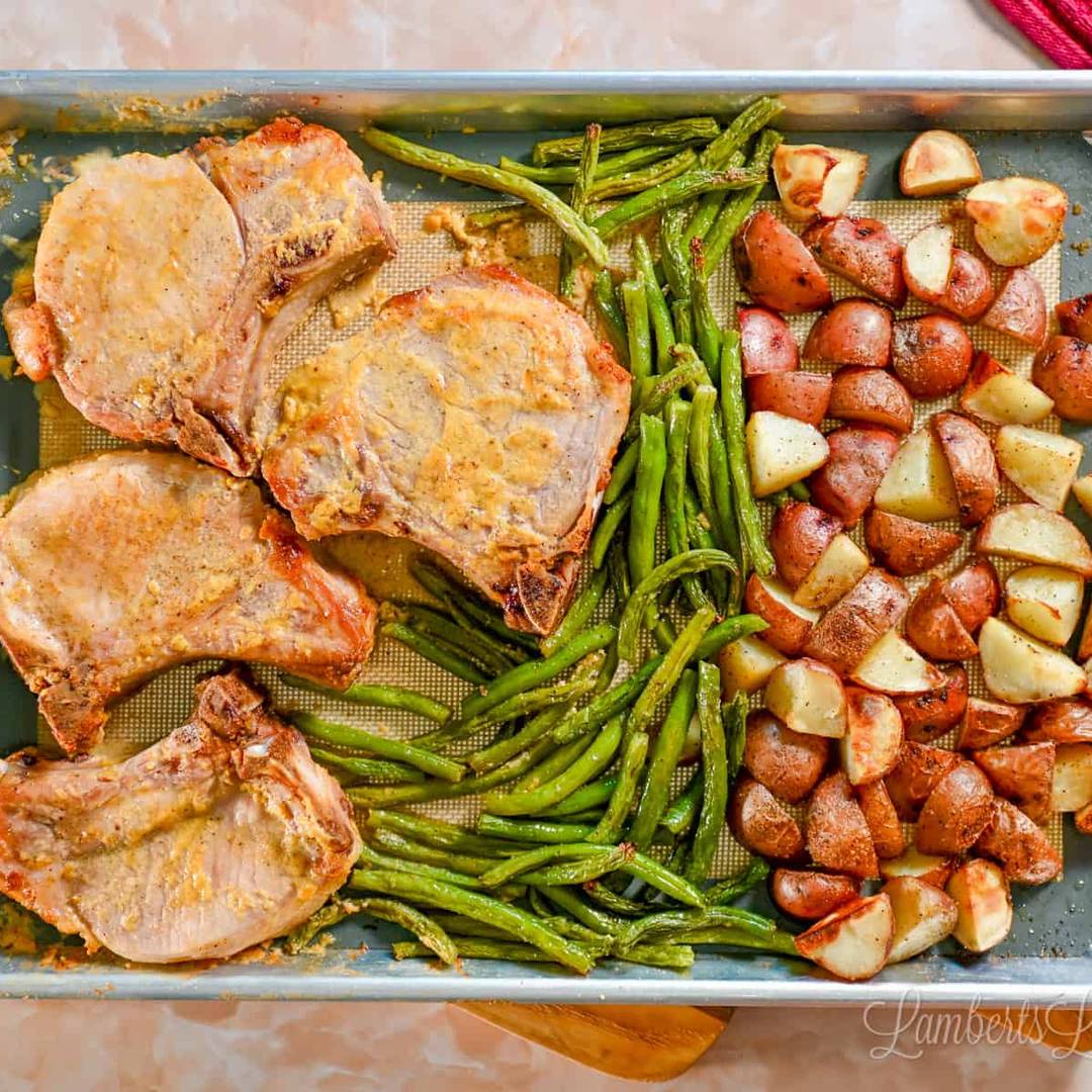 pork chops, green beans, and potatoes on a sheet pan.