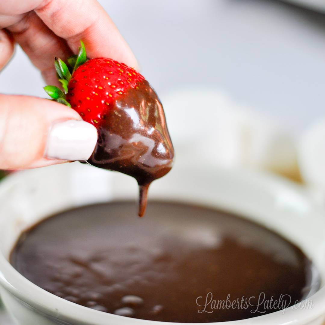 dipping a strawberry in chocolate dip.
