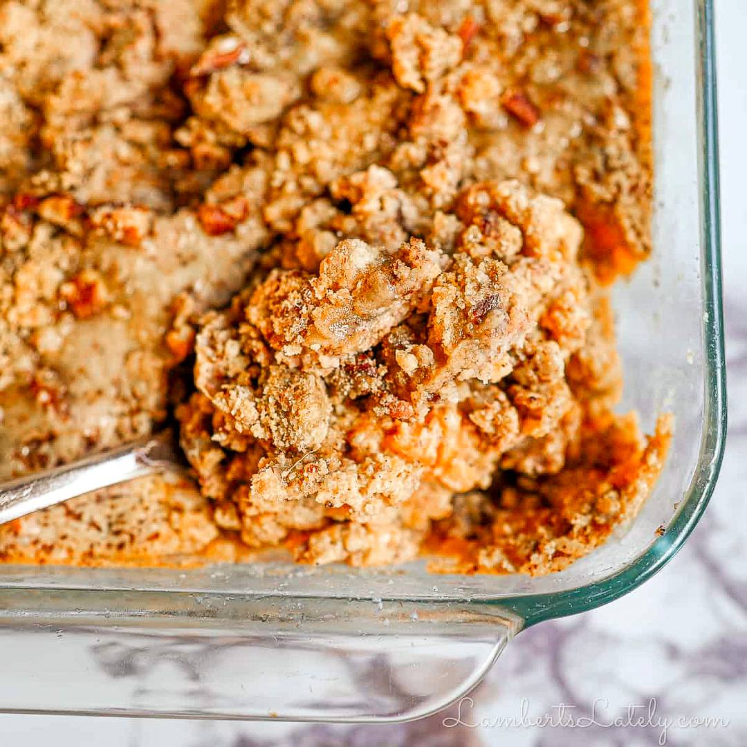 a spoon in a casserole dish of sweet potato casserole.