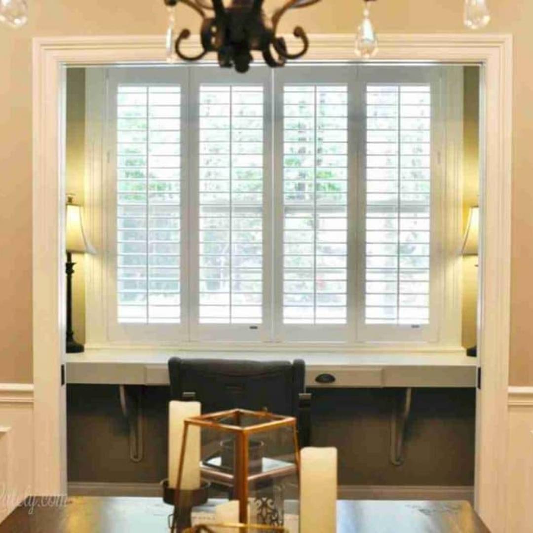 plantation shutters in front of a desk.