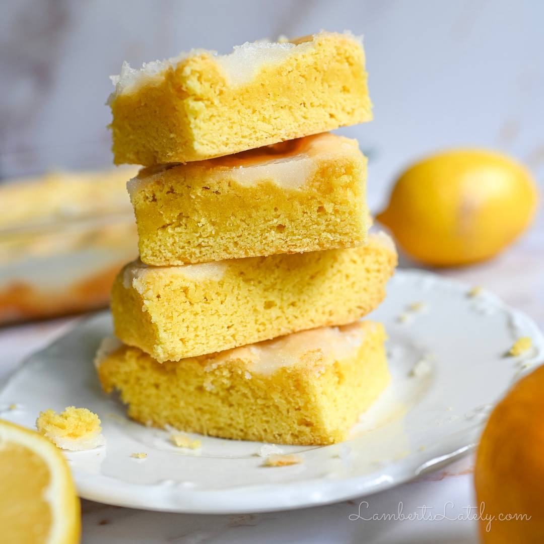 lemon brownies stacked on a plate.