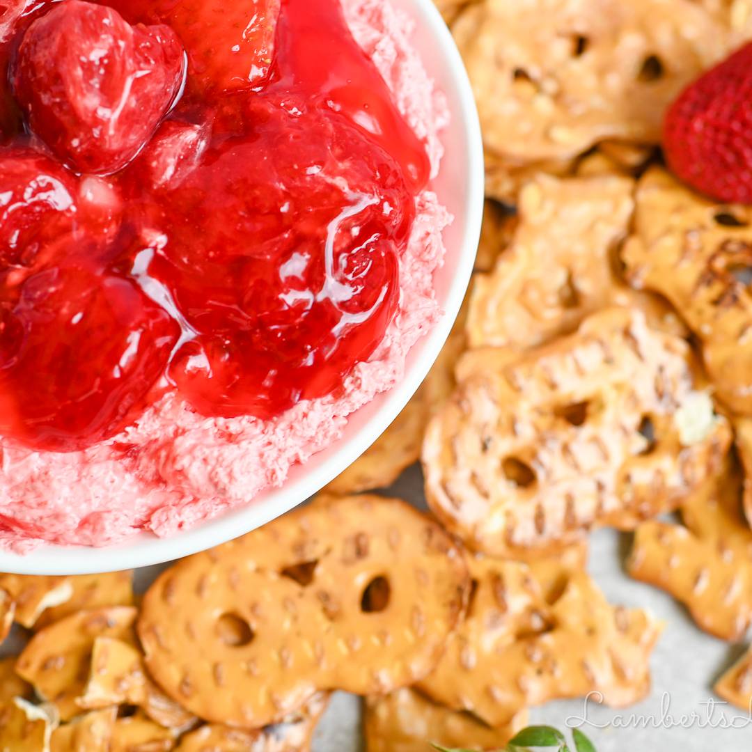 strawberry pretzel dip covered in strawberry pie filling, surrounded by pretzel slims.