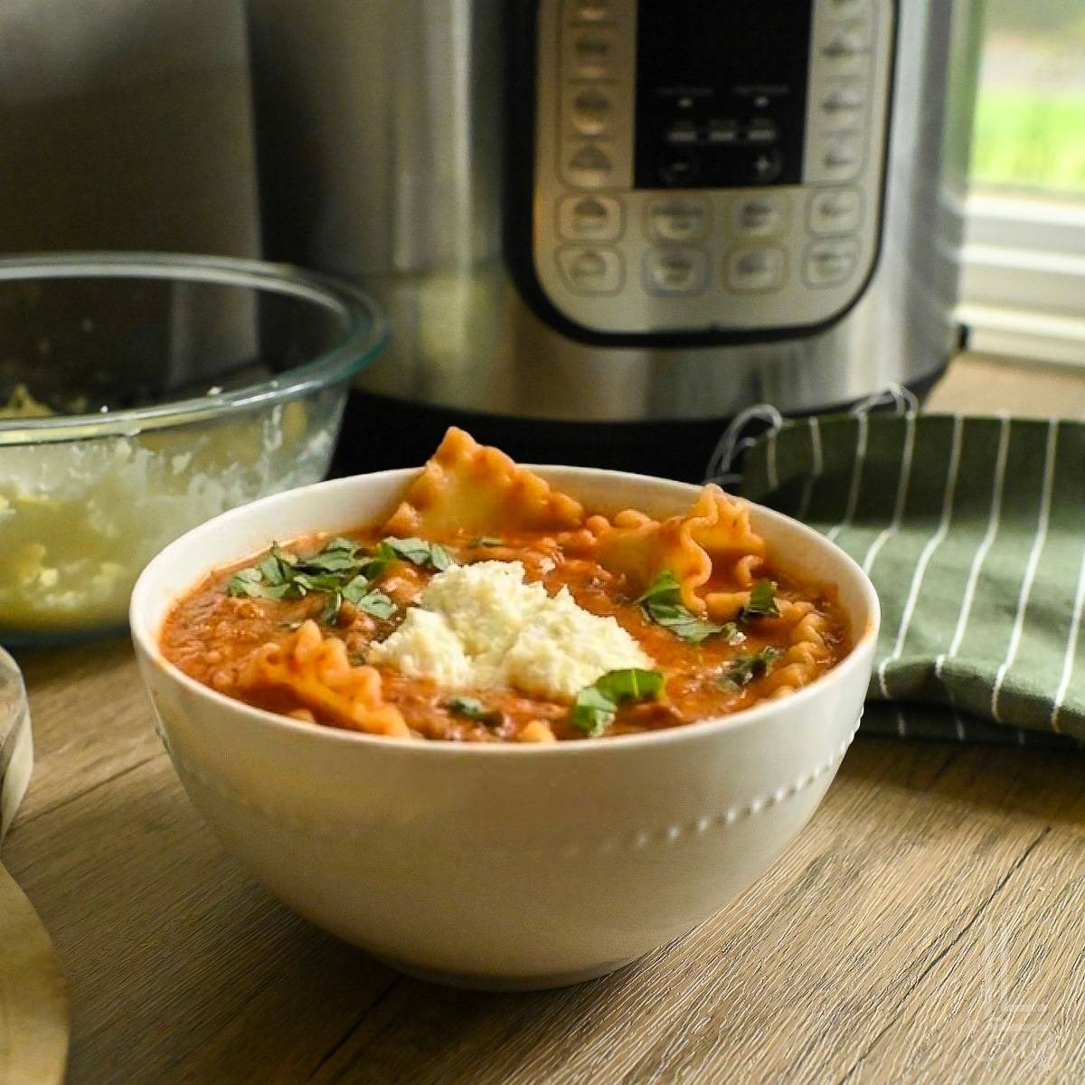 bowl of lasagna soup in front of an instant pot.