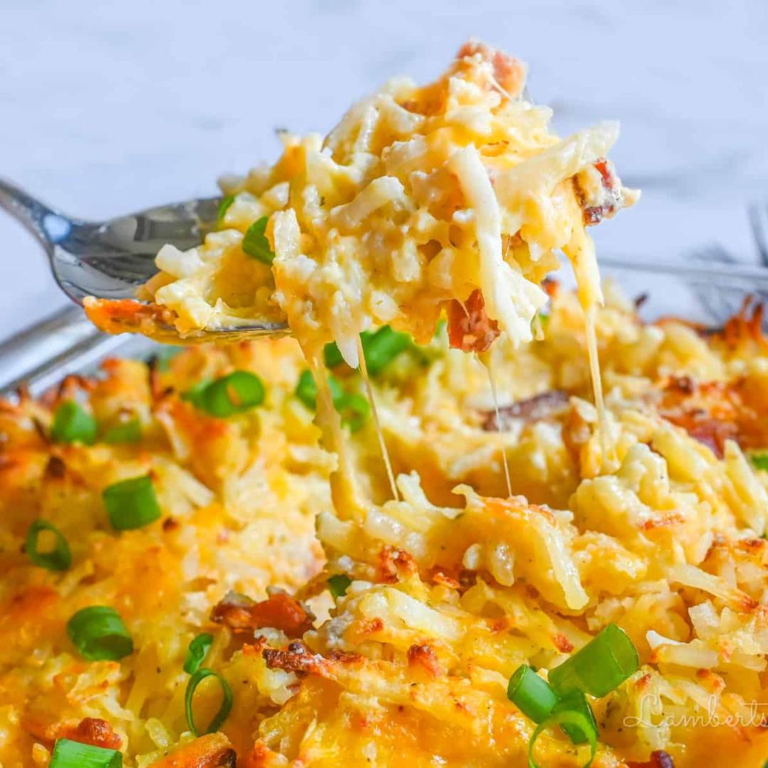 lifting a spoonful of crack potatoes out of a casserole dish.