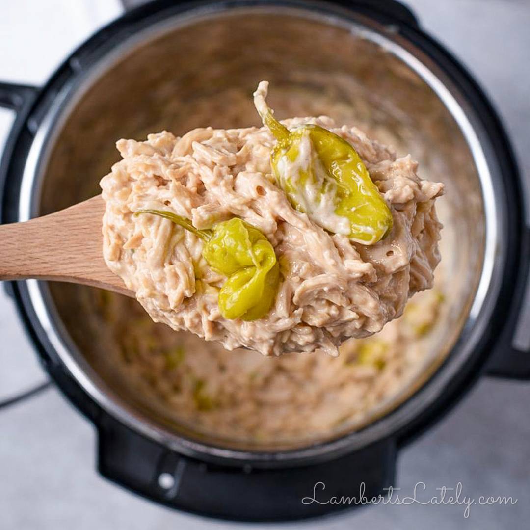 Creamy Instant Pot Mississippi chicken with pepperoncini peppers on a wooden spoon.