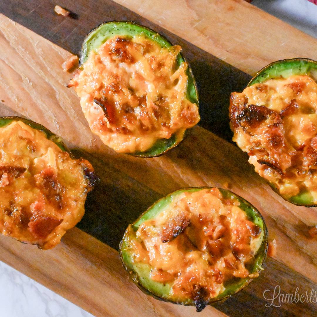 baked avocados with cheese and bacon on a cutting board.