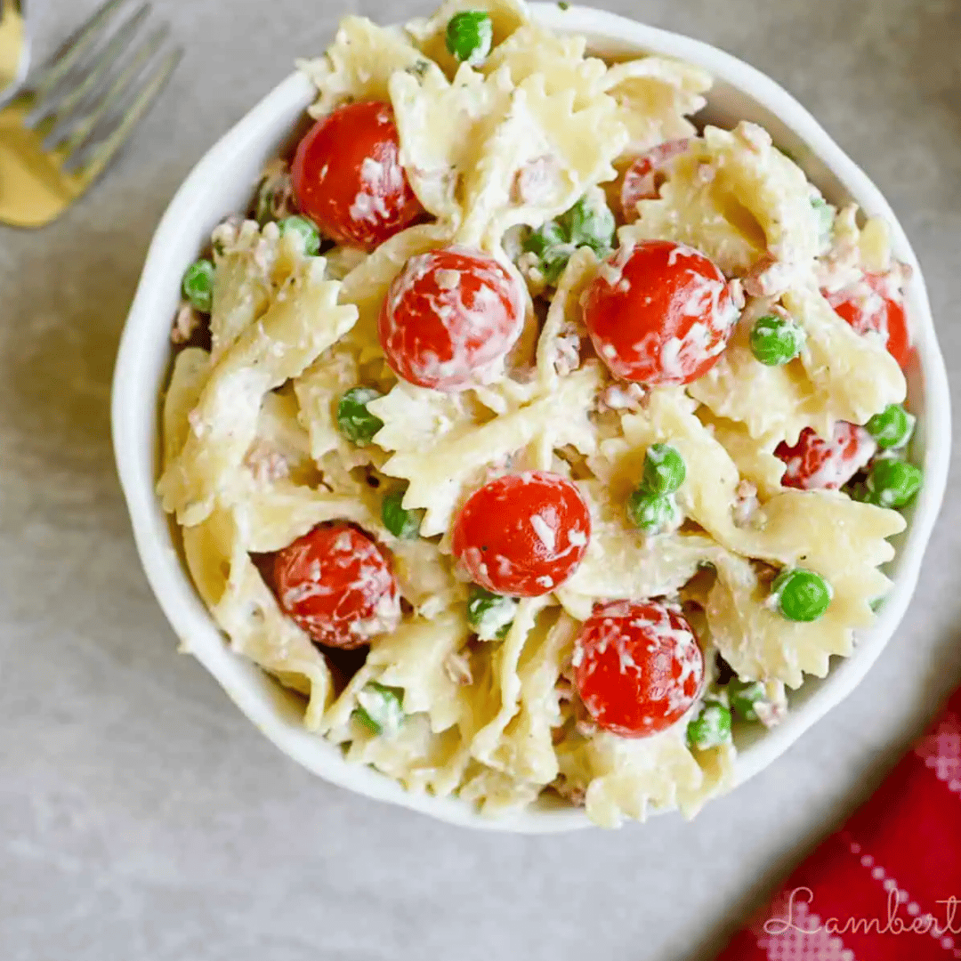 bacon ranch pasta salad with tomatoes and peas in a bowl.