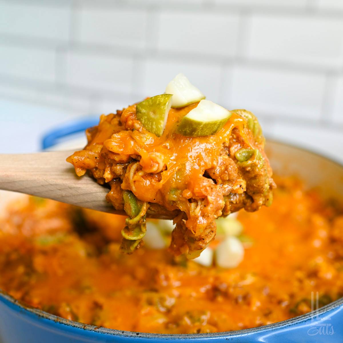 holding a spoonful of cheeseburger pasta over a cooking dish.