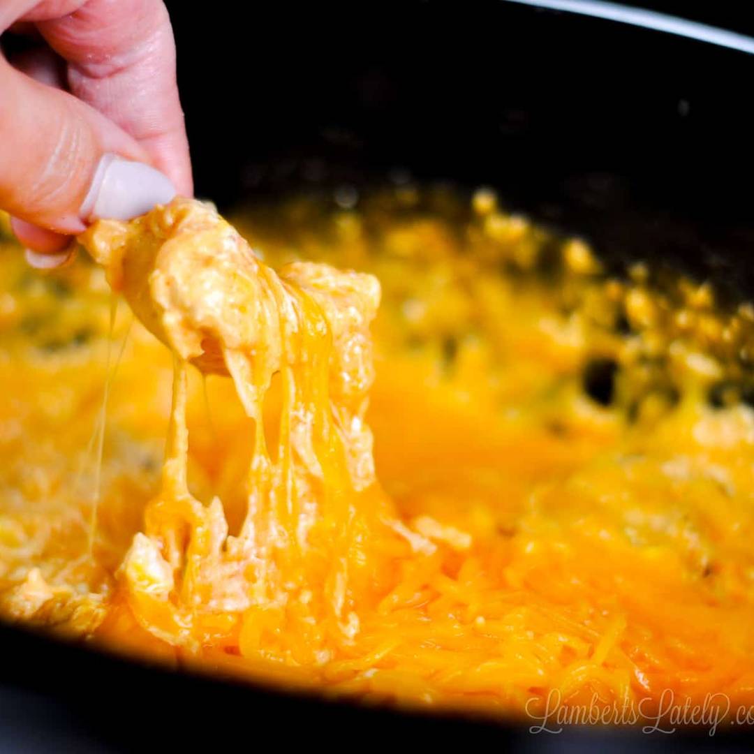 scooping buffalo chicken dip out of a crock pot with a chip.