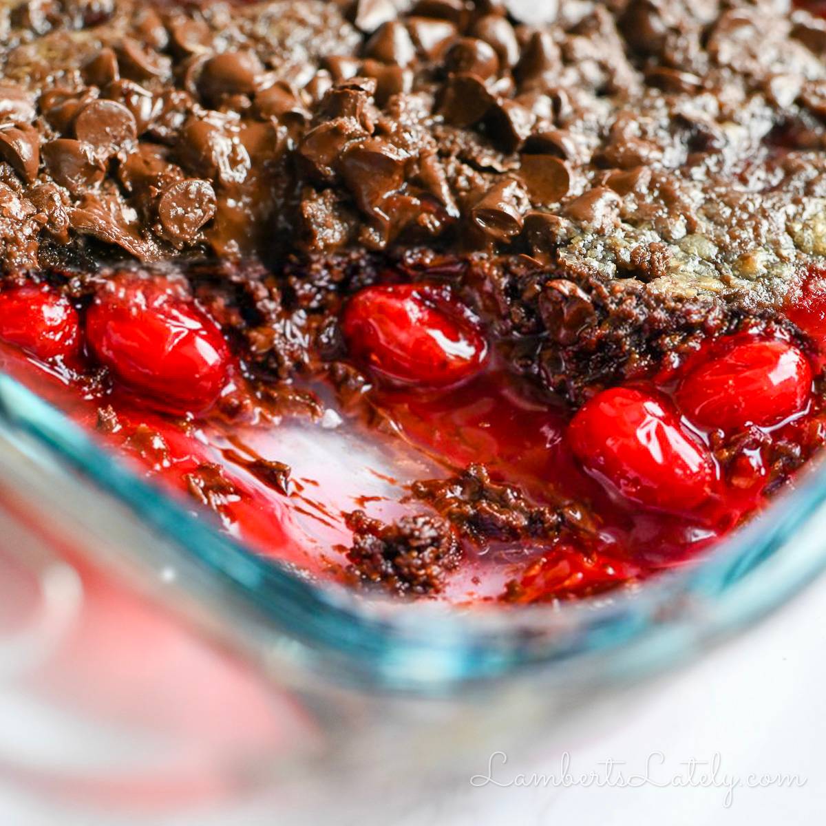 corner of a cherry chocolate dump cake in a baking dish with serving removed.