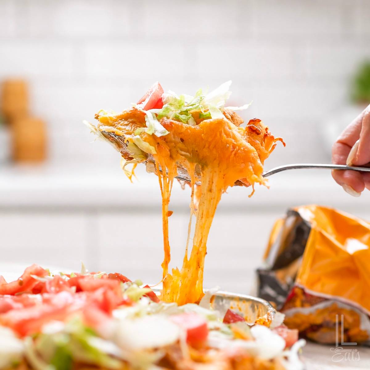 holding a spoonful of cheesy walking taco casserole.