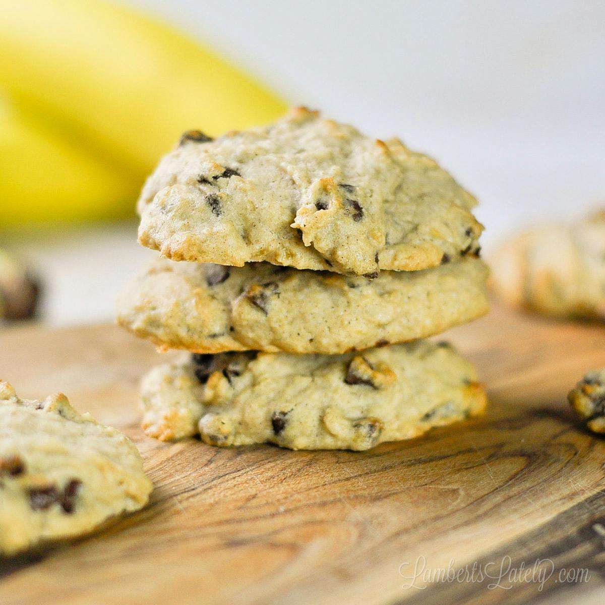 three banana bread cookies stacked on a cutting board.