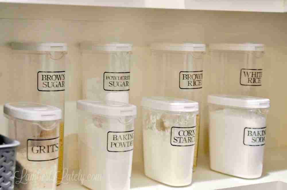a row of clear pantry canisters, labeled, in a pantry.