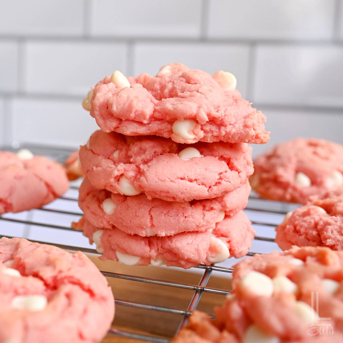 strawberry cake mix cookies stacked on a baking rack.