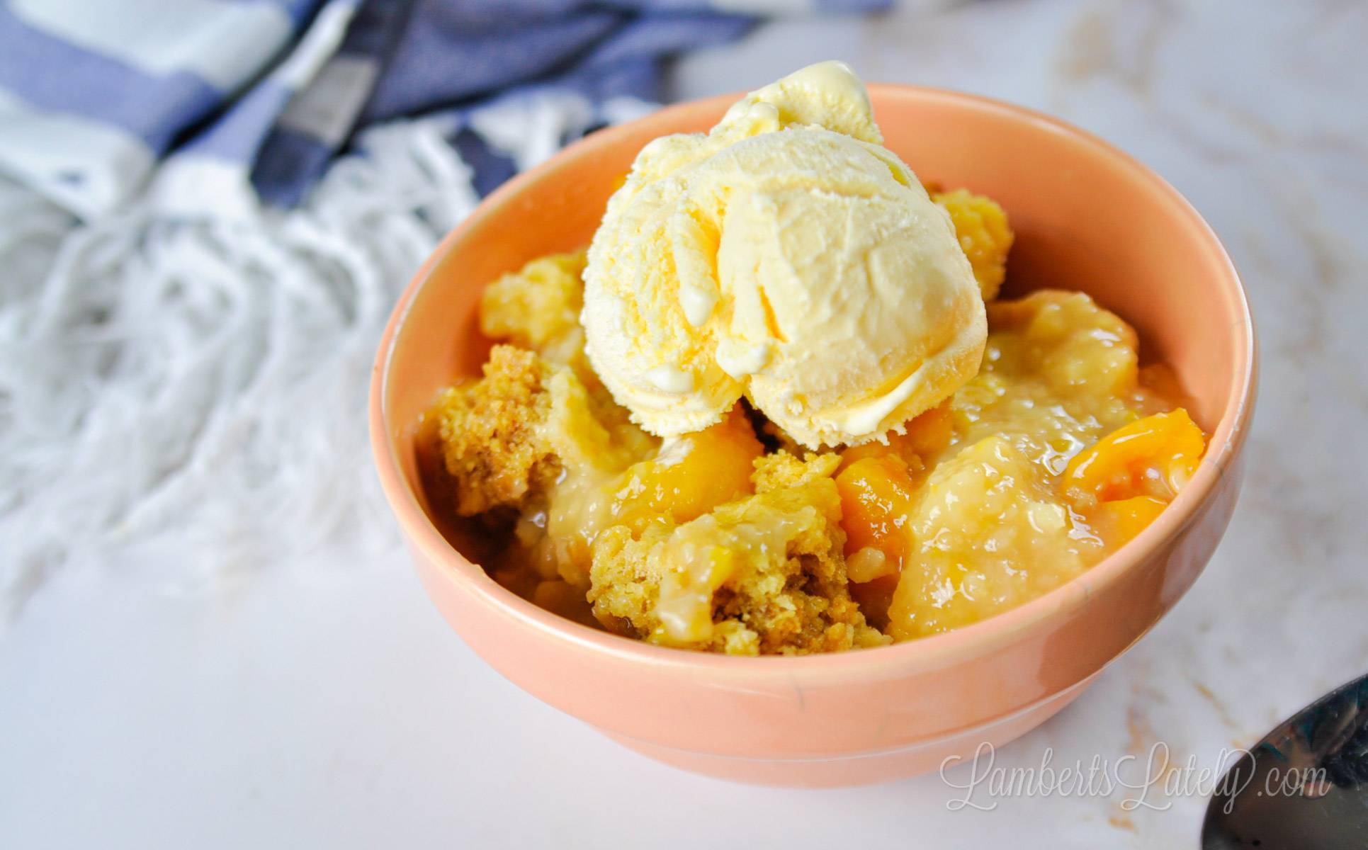 bowl of crock pot peach cobbler topped with ice cream.