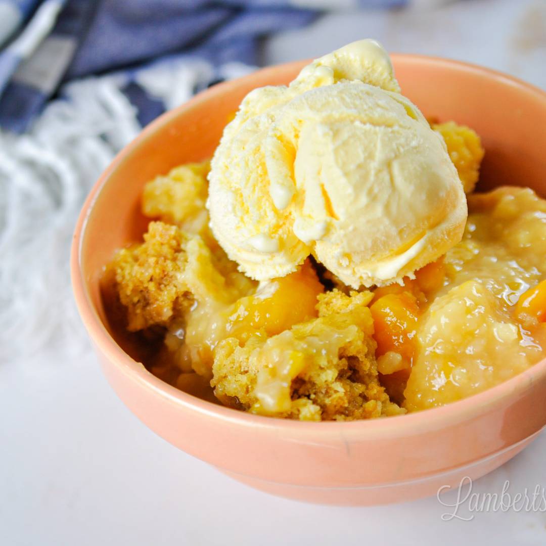 peach cobbler in a bowl, topped with a scoop of ice cream.