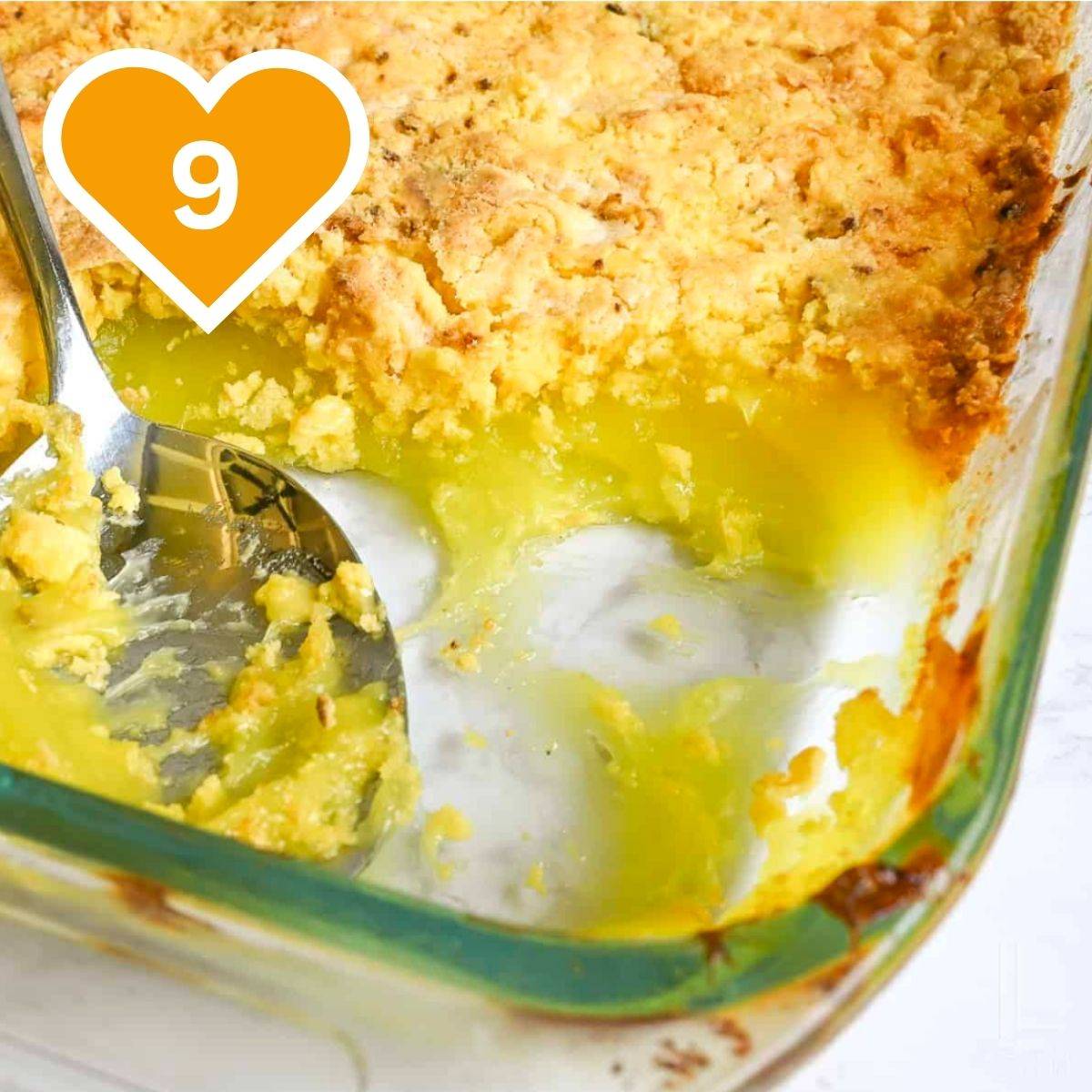 Golden lemon dump cake in a glass baking dish with a spoonful scooped out to show the creamy lemon filling.